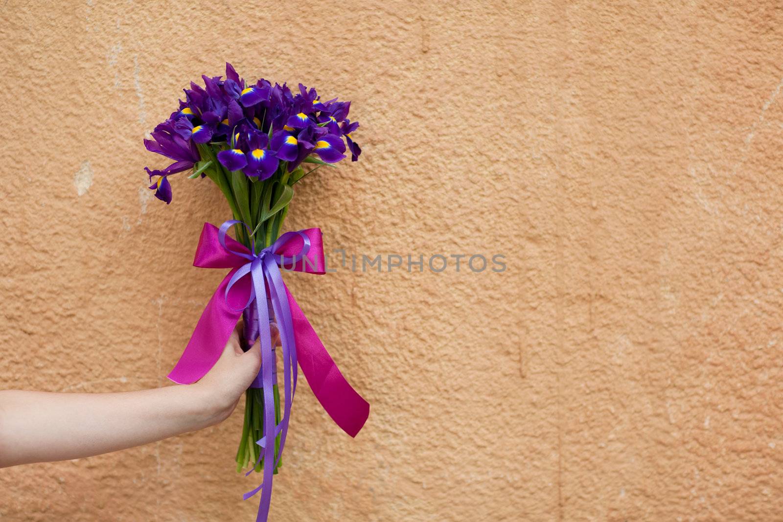 wedding bouquet in the hand of the bride by the wall