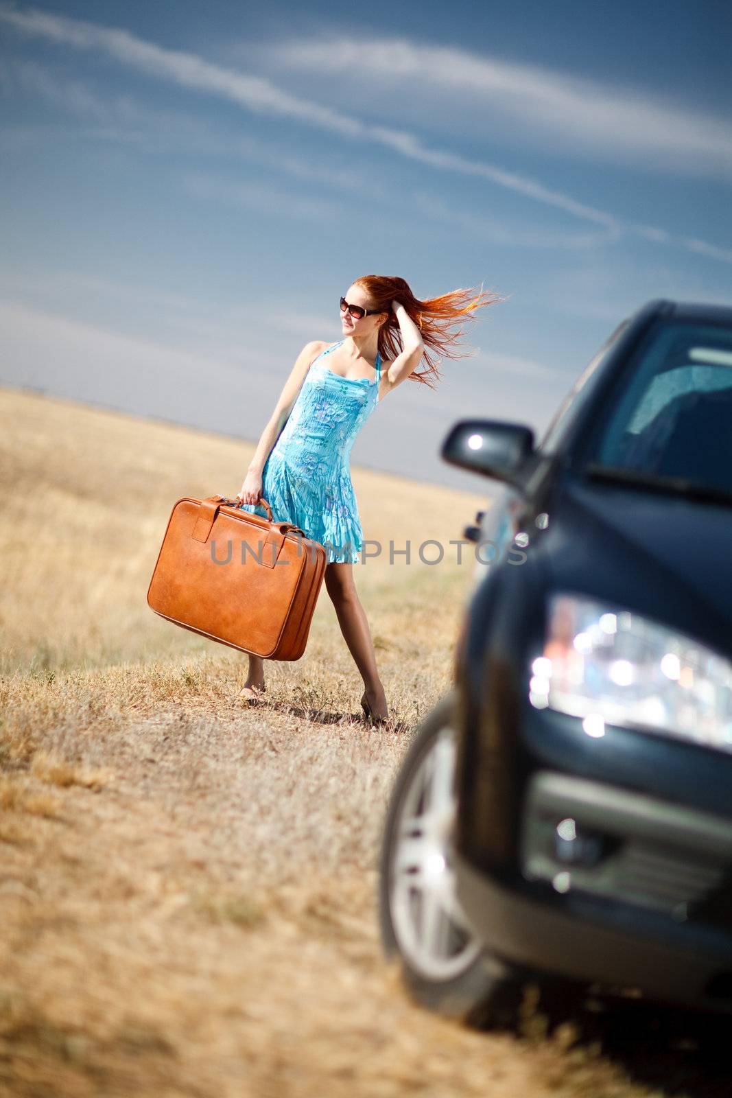 laughing girl with the suitcase near the car