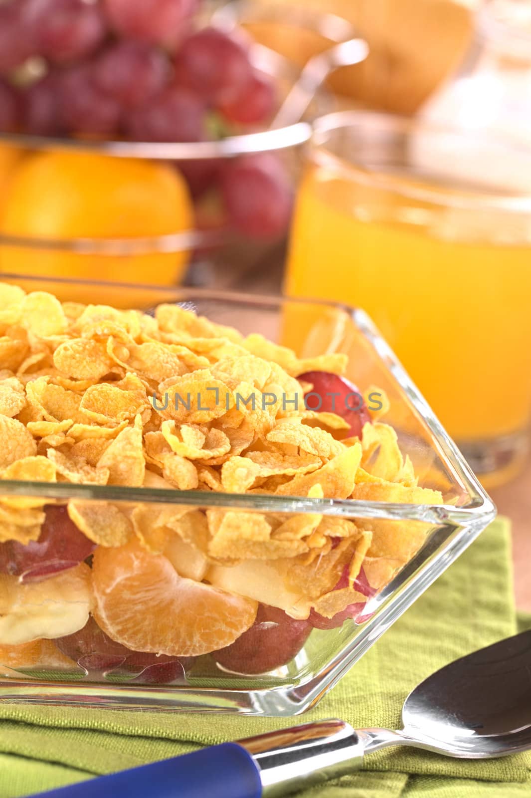 Fresh fruits (banana, apple, mandarine and grape) with corn flakes on top (Selective Focus, Focus one third into the corn flakes)