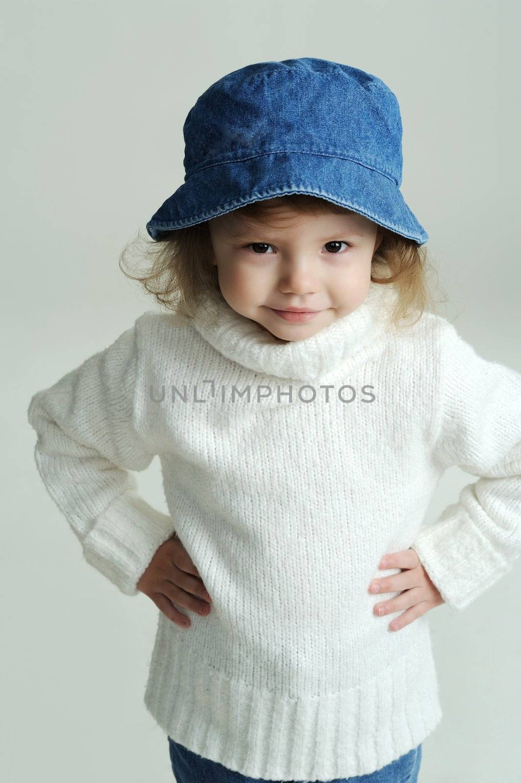 An image of a little girl in a blue hat and white jumper