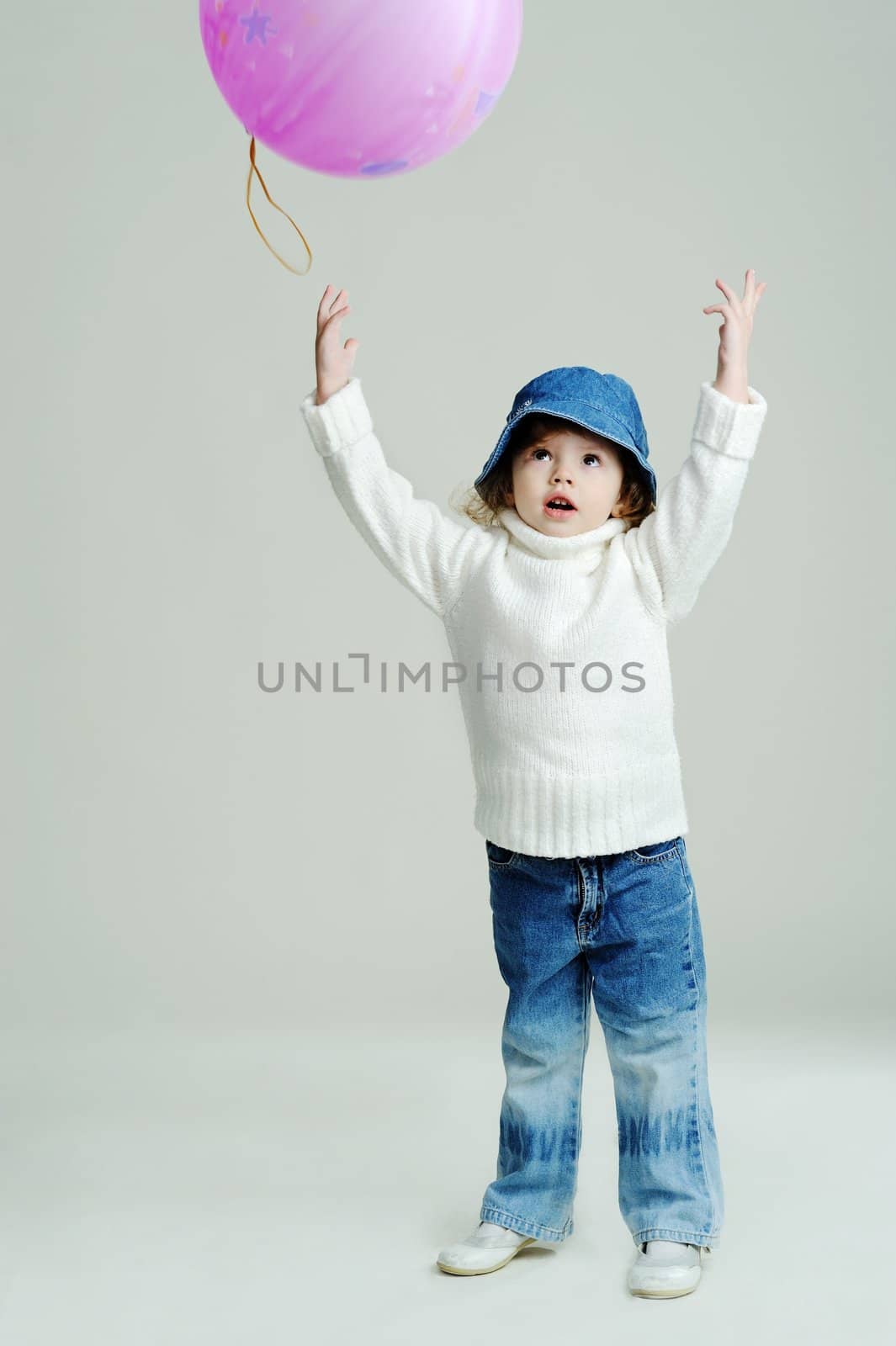 An image of a little girl in a hat and white jumper with balloon