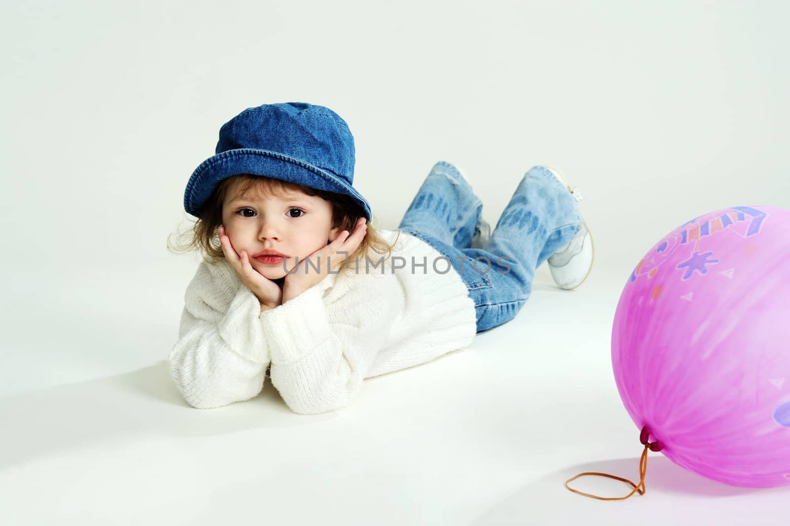 An image of a sad little girl in a hat and white jumper