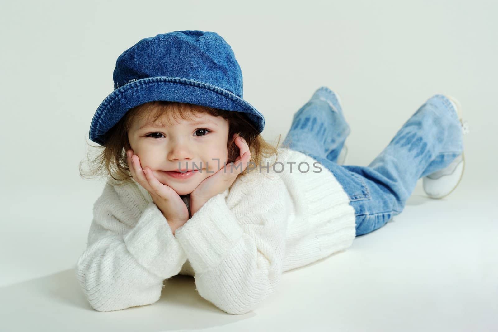 An image of a little girl in a hat and white jumper