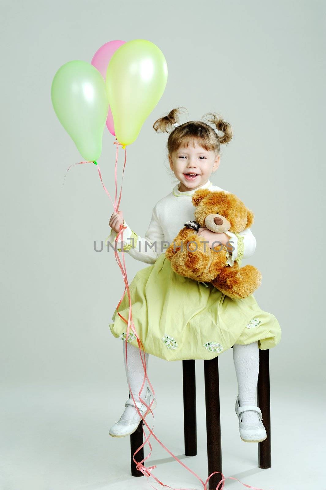 A portrait of a little girl with teddy-bear and balloons