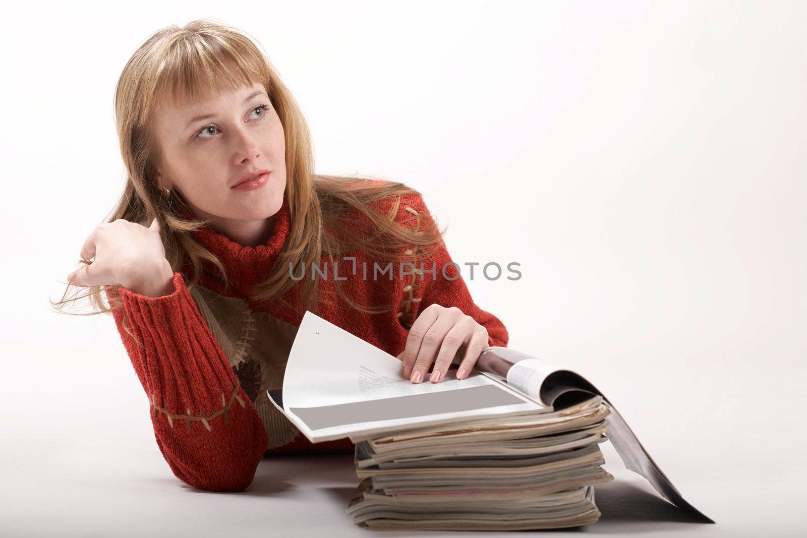 A beautiful girl luing and reading magazines