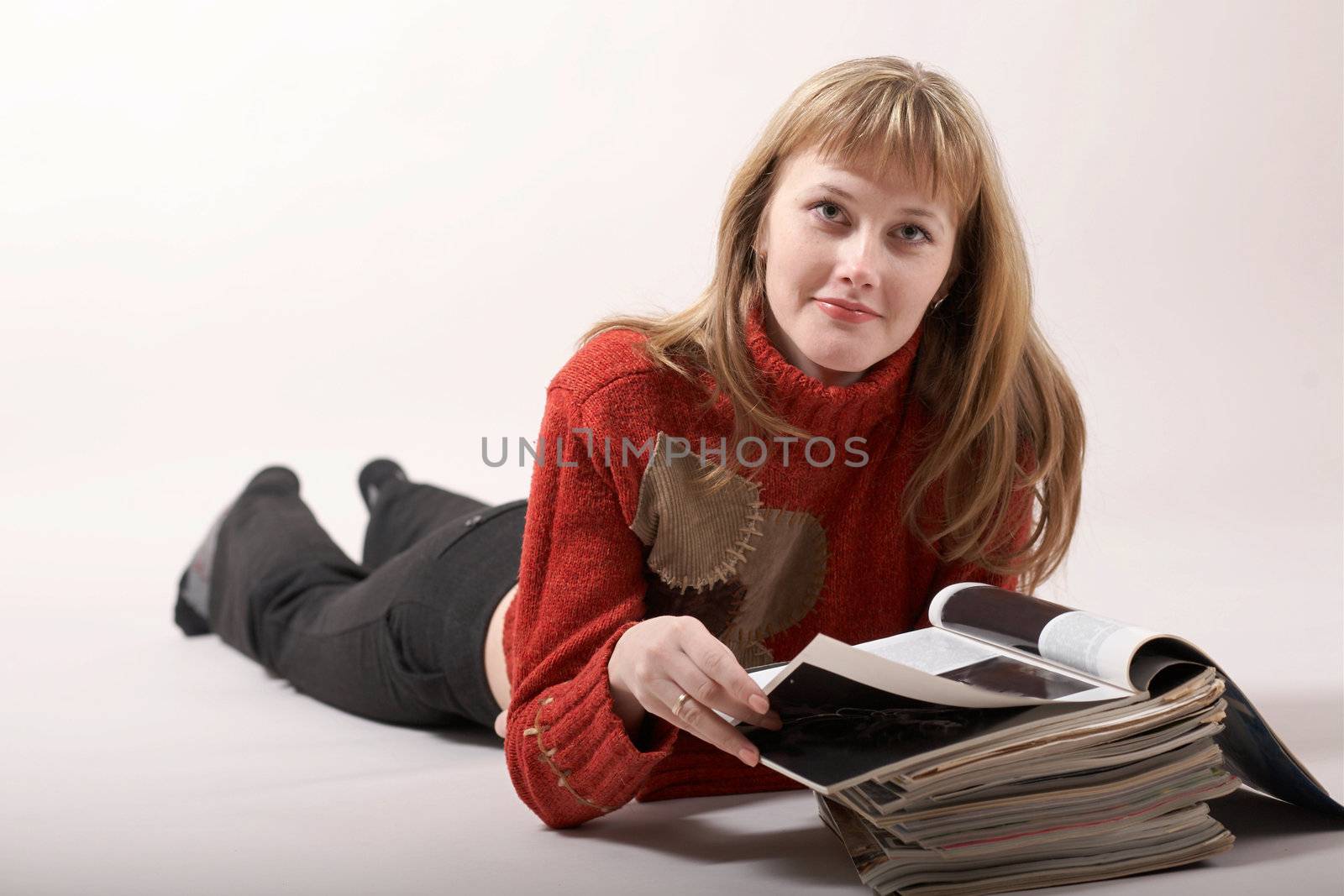 An image of girl luing and reading magazines