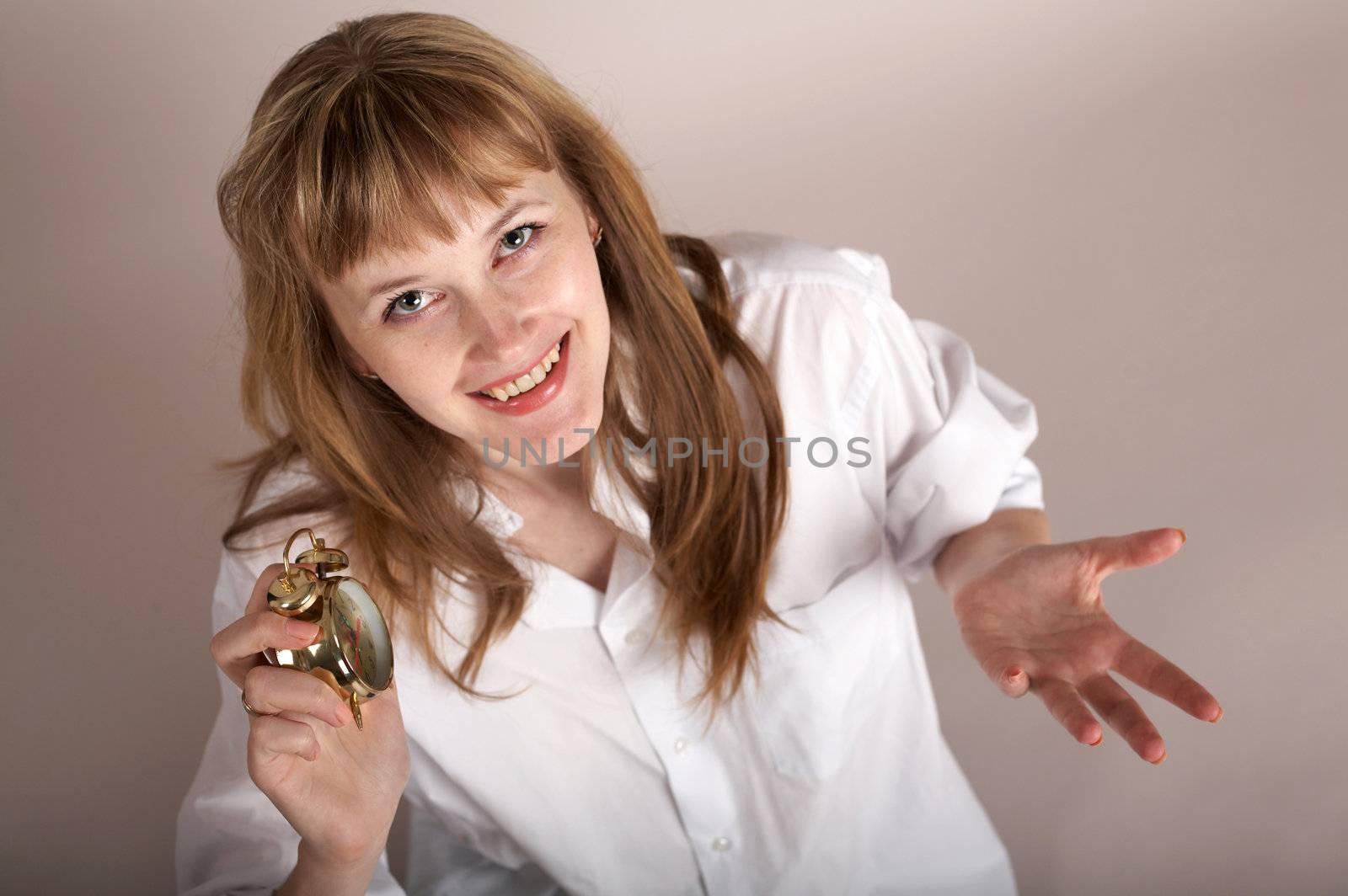 A nice woman in a white shirt holding an alarm-clock
