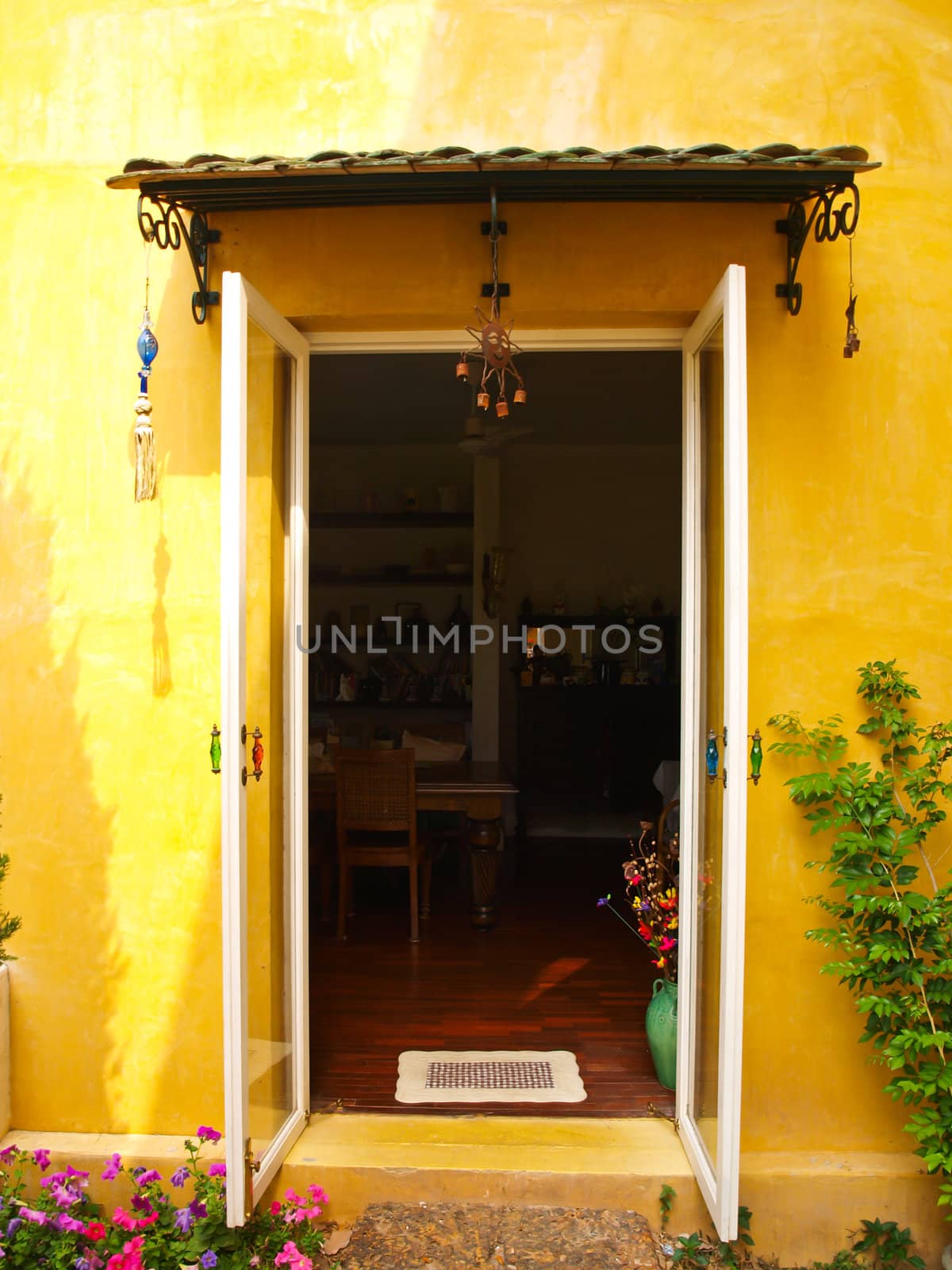 Yellow house wall with opened door and flower by gururugu