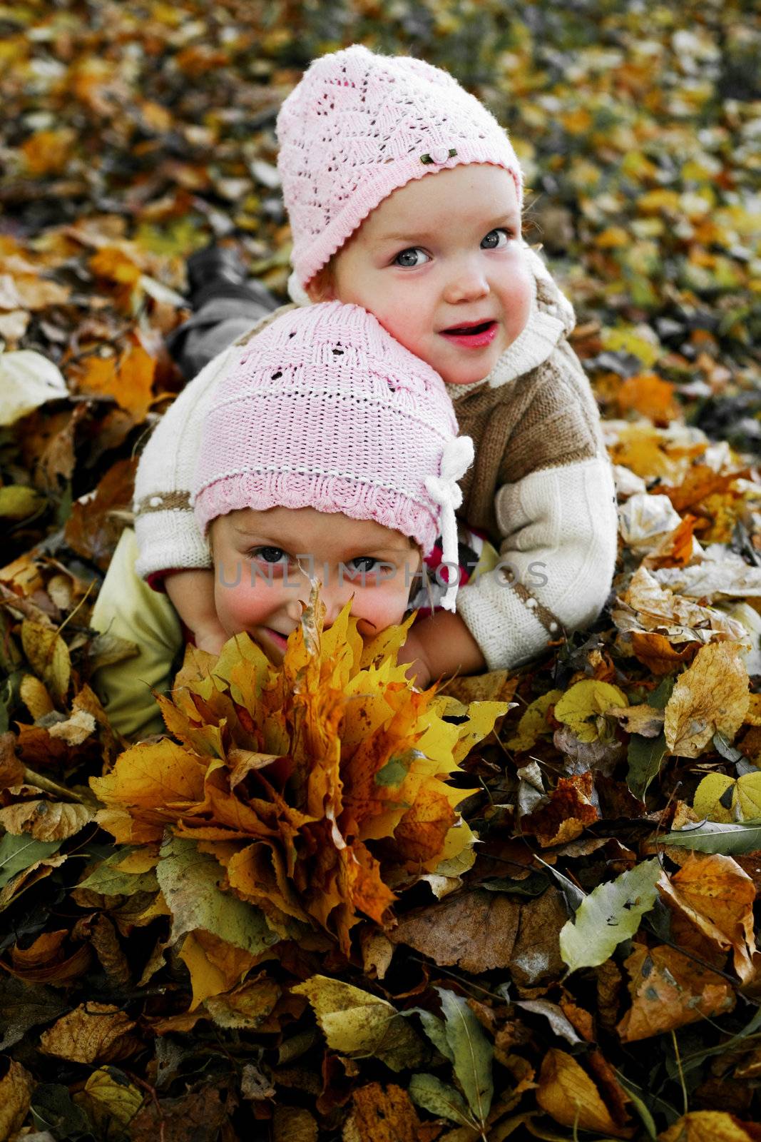 Two sisters playing with yellow leaves in a park