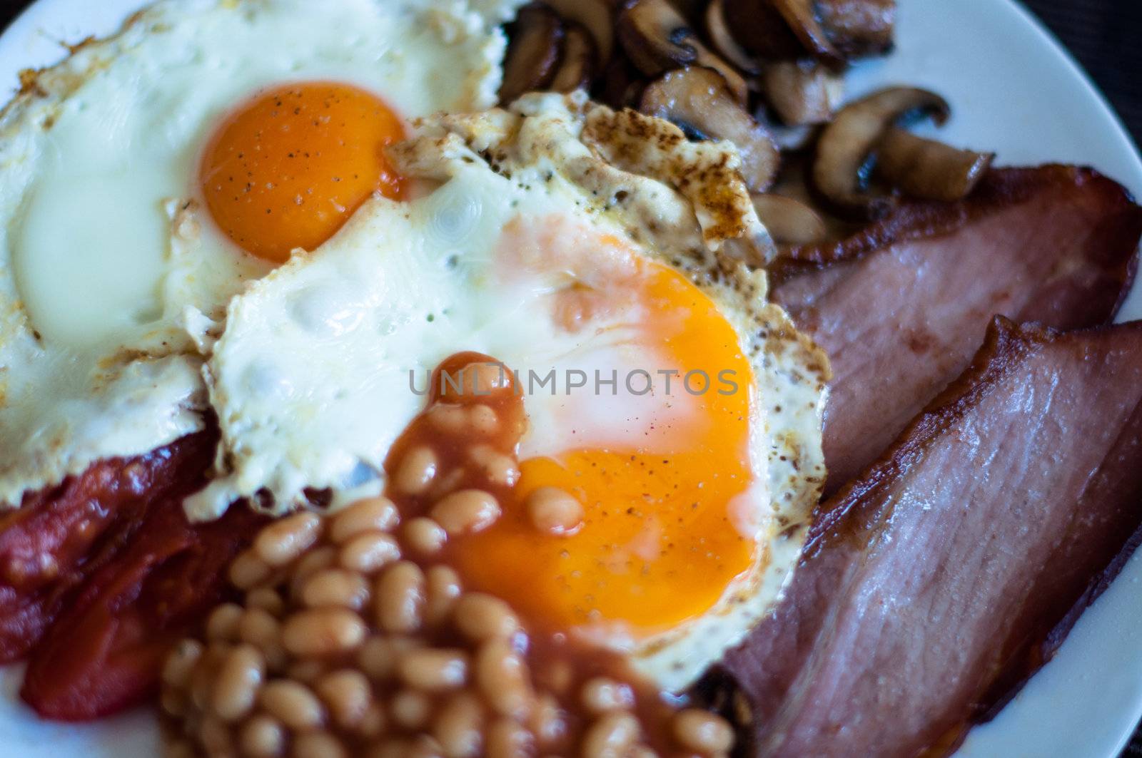 Traditional English breakfast - fried bacon, mushrooms, eggs, baked beens and tomatos