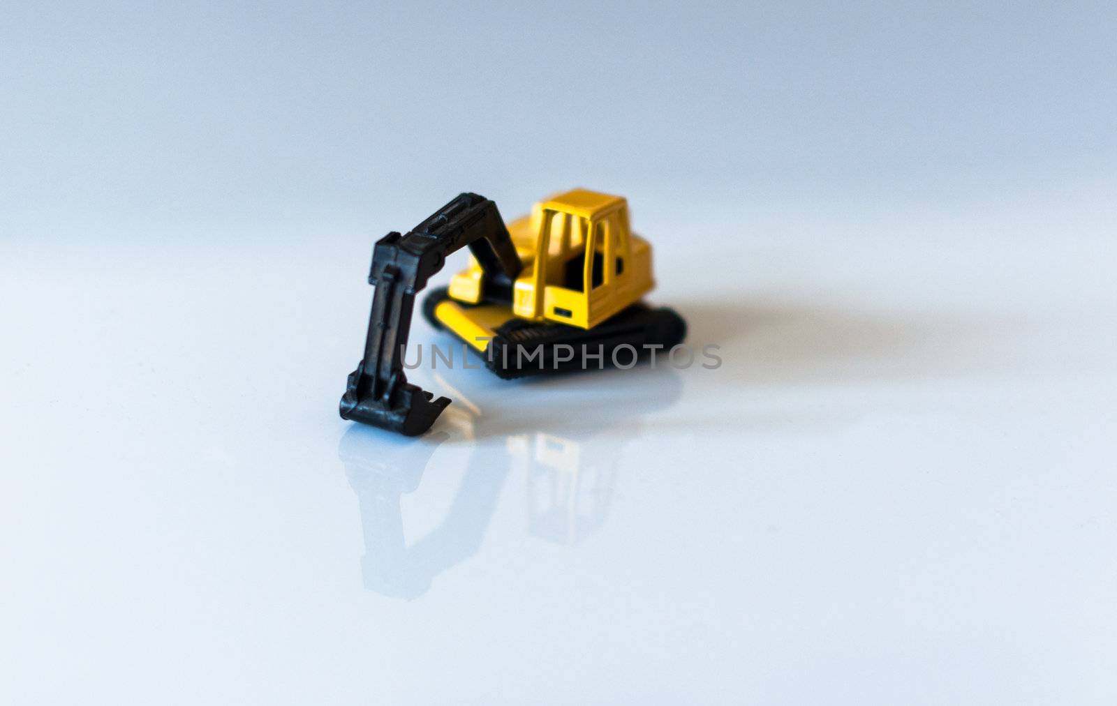 yellow toy excavator with great reflection on white background