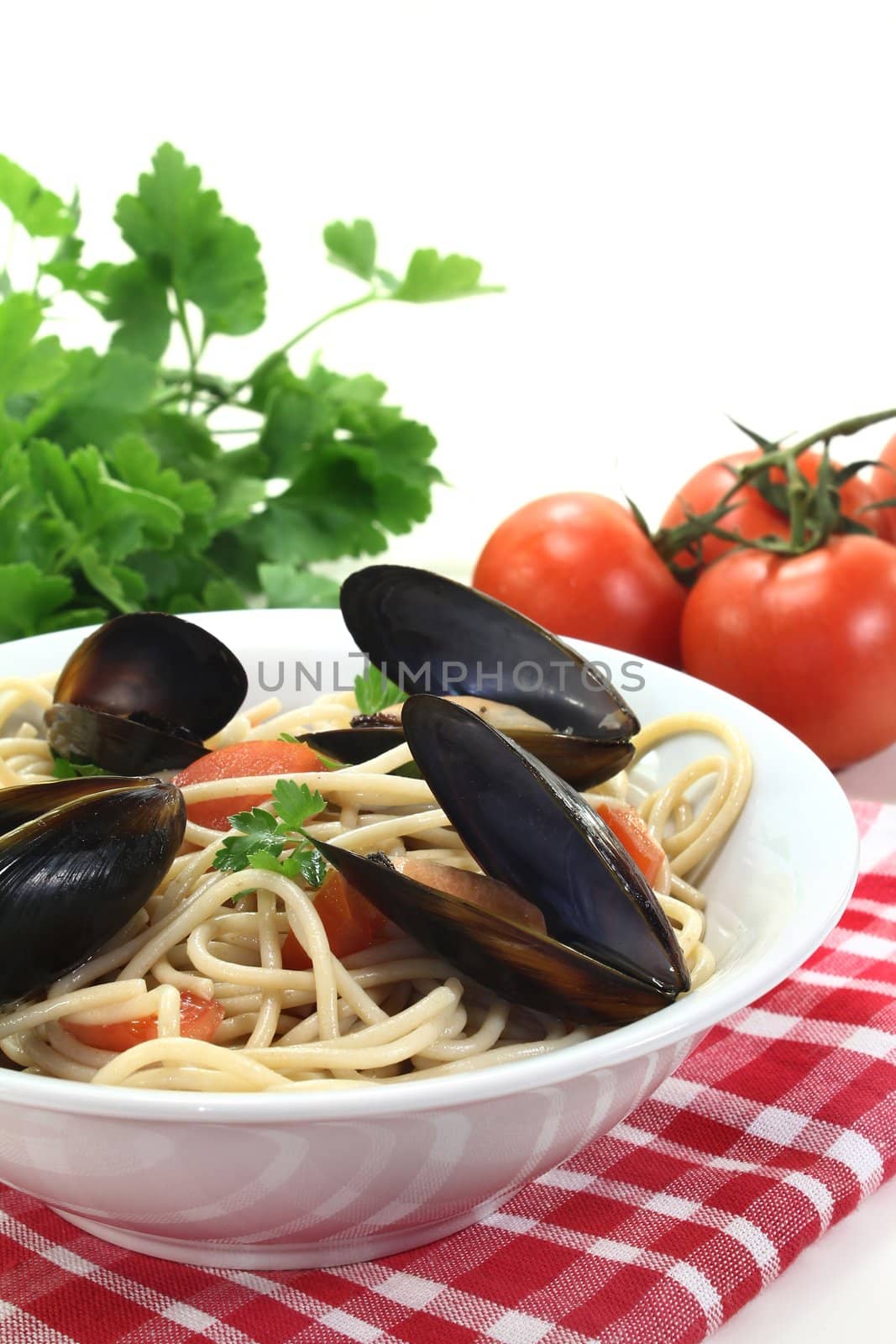 cooked Spaghetti with tomatoes, mussels and fresh parsley on a light background