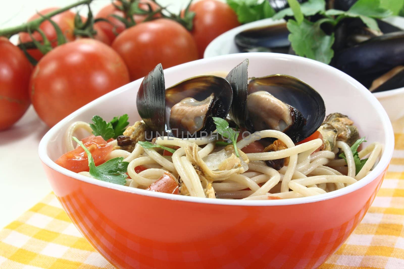 cooked Spaghetti with tomatoes, mussels and parsley on a light background