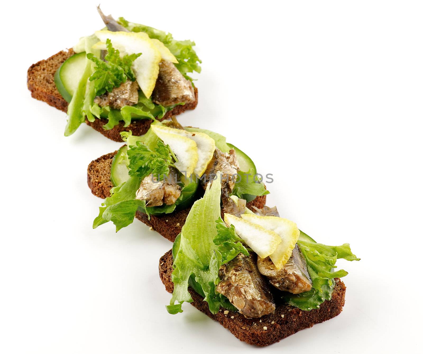 Three smoked sardines sandwiches with cucumber and whole wheat bread isolated on white background