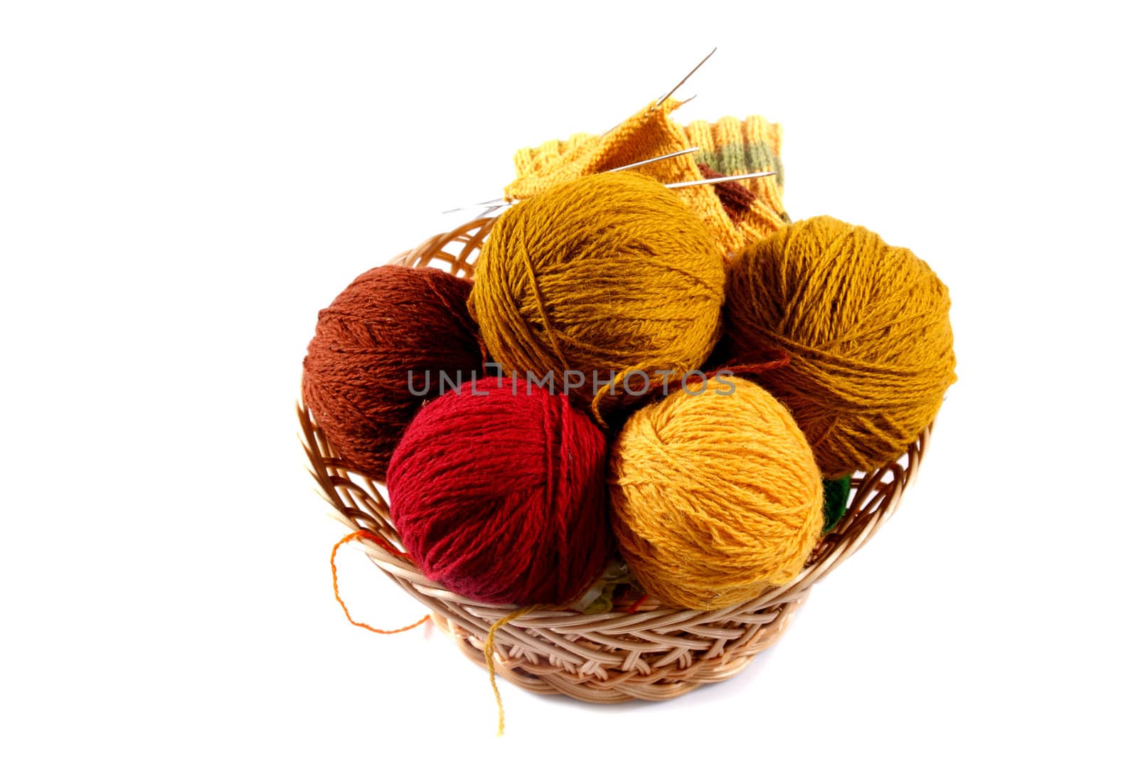 colored wool balls in wicker basket on a white background