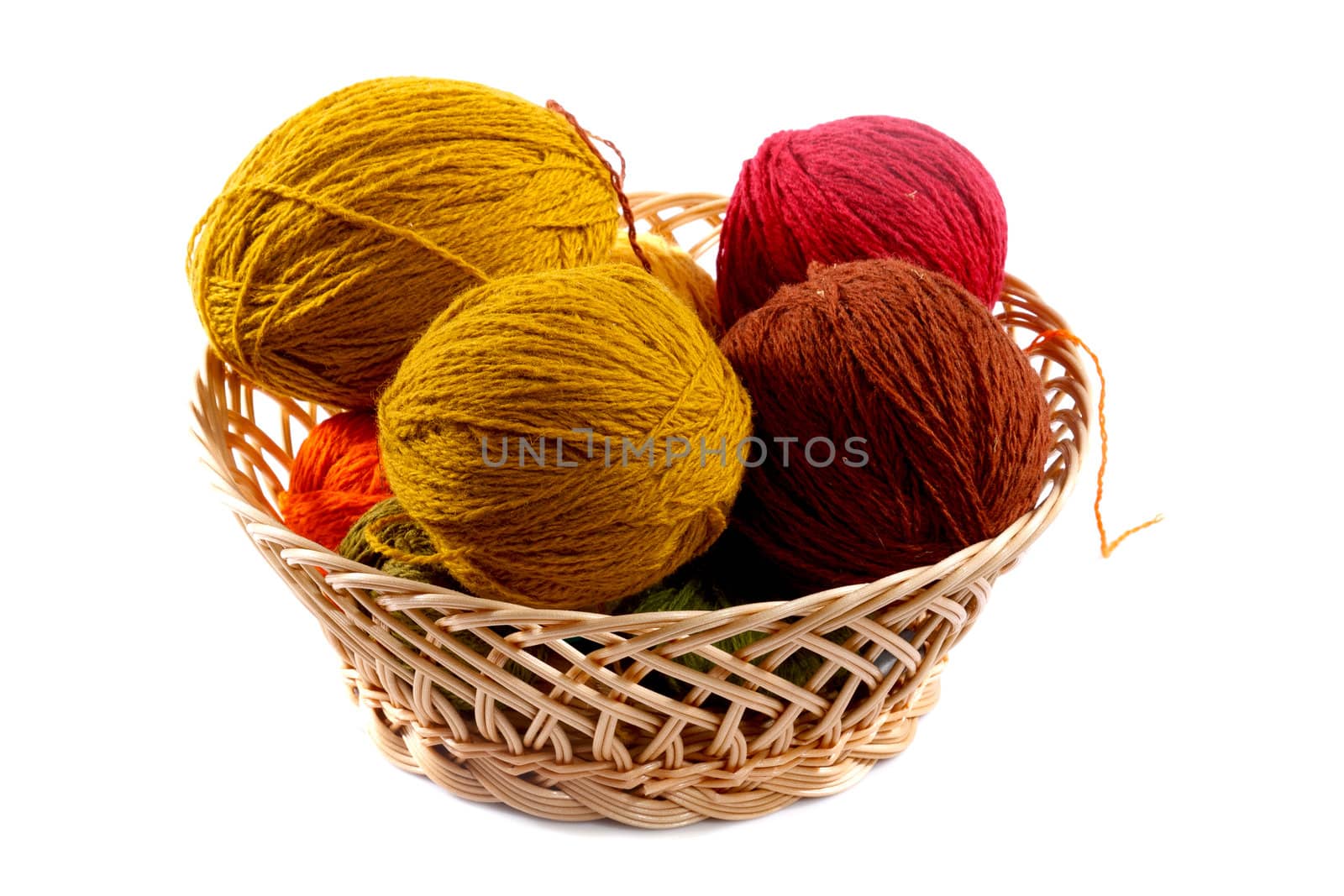 colored wool balls in wicker basket on a white background