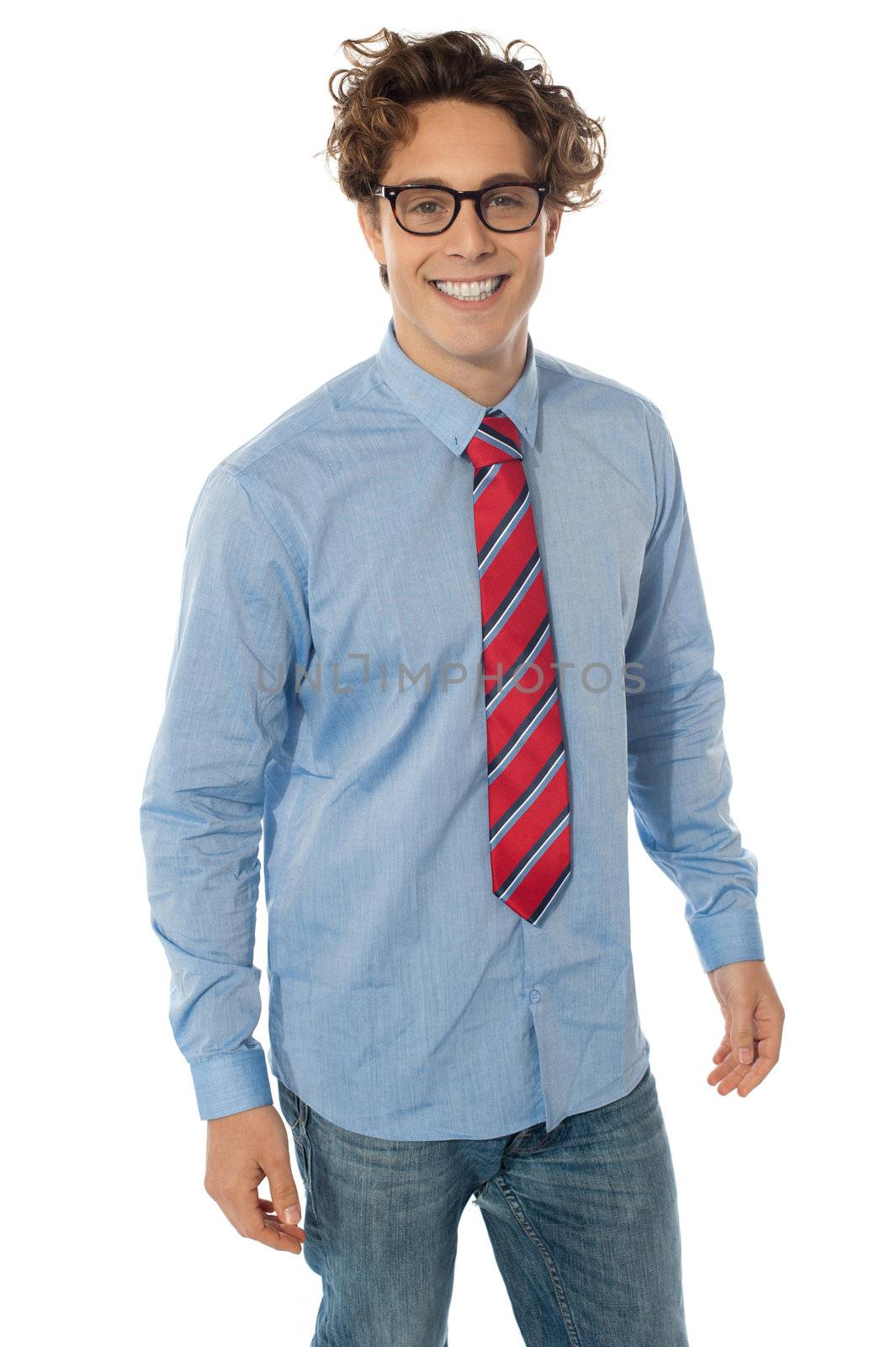 A young teenager in blue shirt, jeans and tie standing in the studio