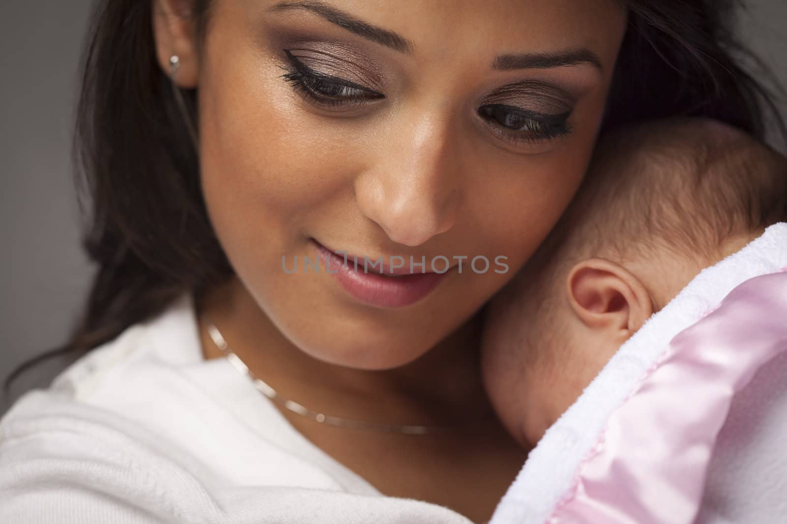 Young Attractive Ethnic Woman Holding Her Newborn Baby Under Dramatic Lighting.