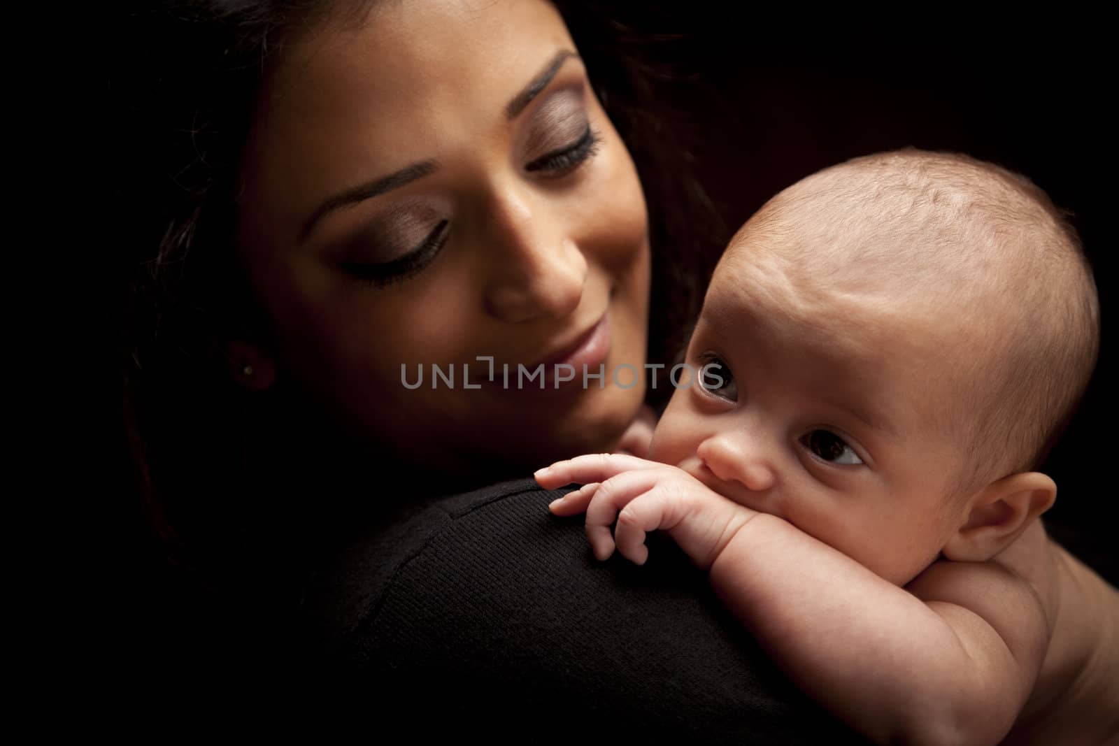 Young Attractive Ethnic Woman Holding Her Newborn Baby Under Dramatic Lighting.