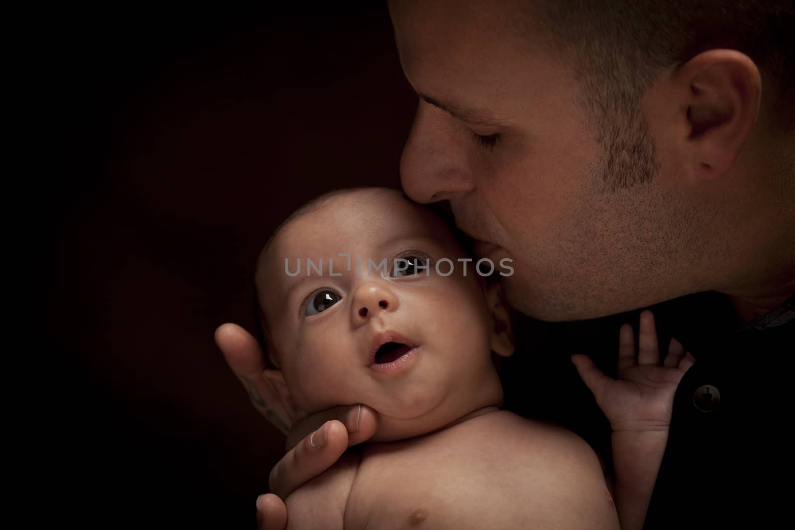 Happy Young Father Holding His Mixed Race Newborn Baby Under Dramatic Lighting.