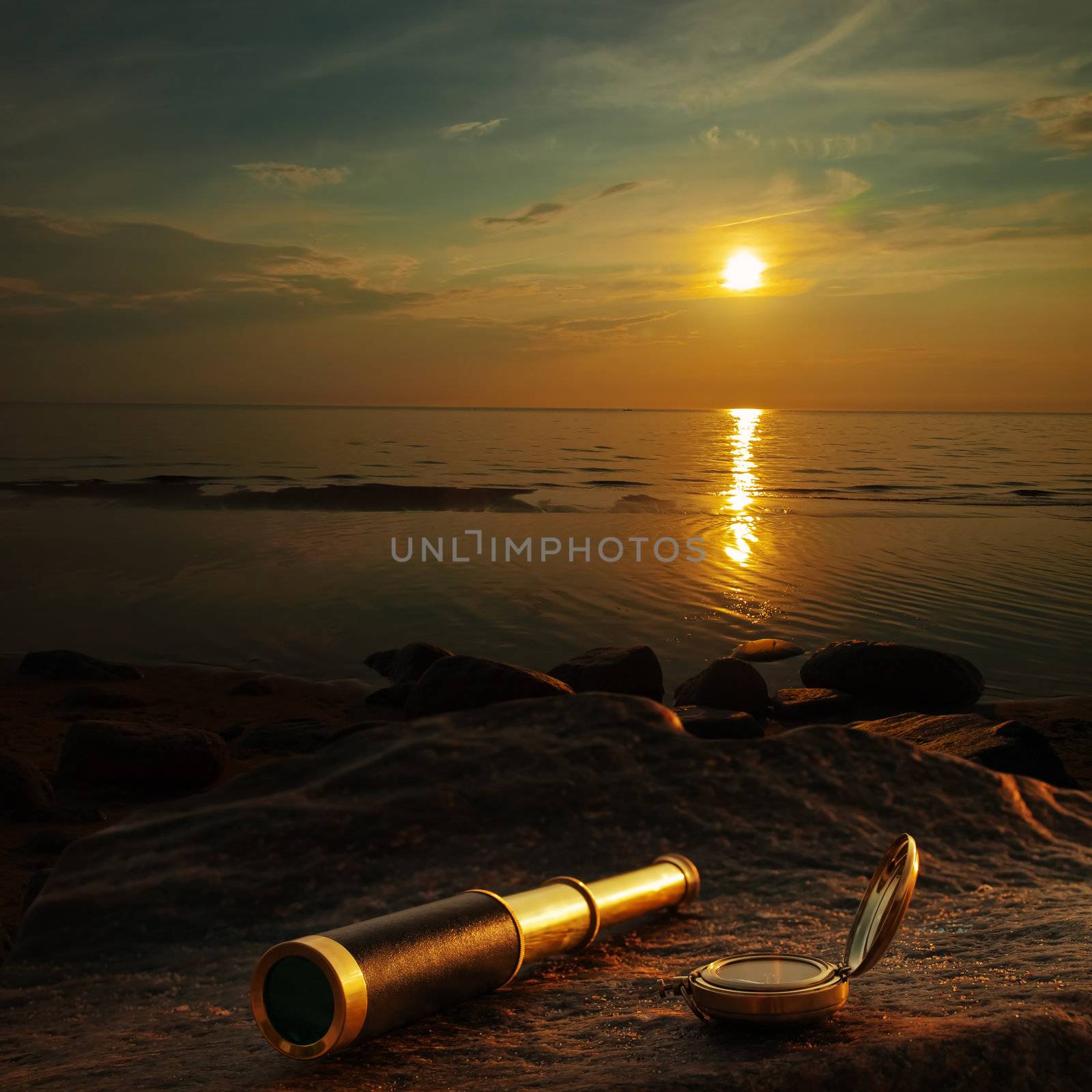 antique brass telescope and compass at sea coast stone