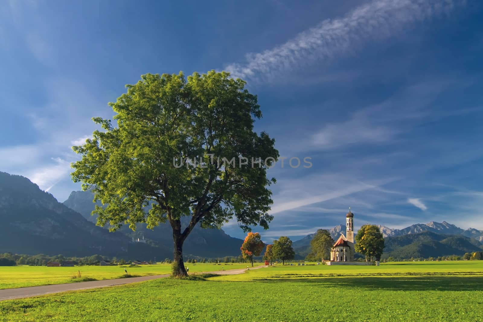 Autumn landscape with road, tree, church, mountains and sky on backgruond