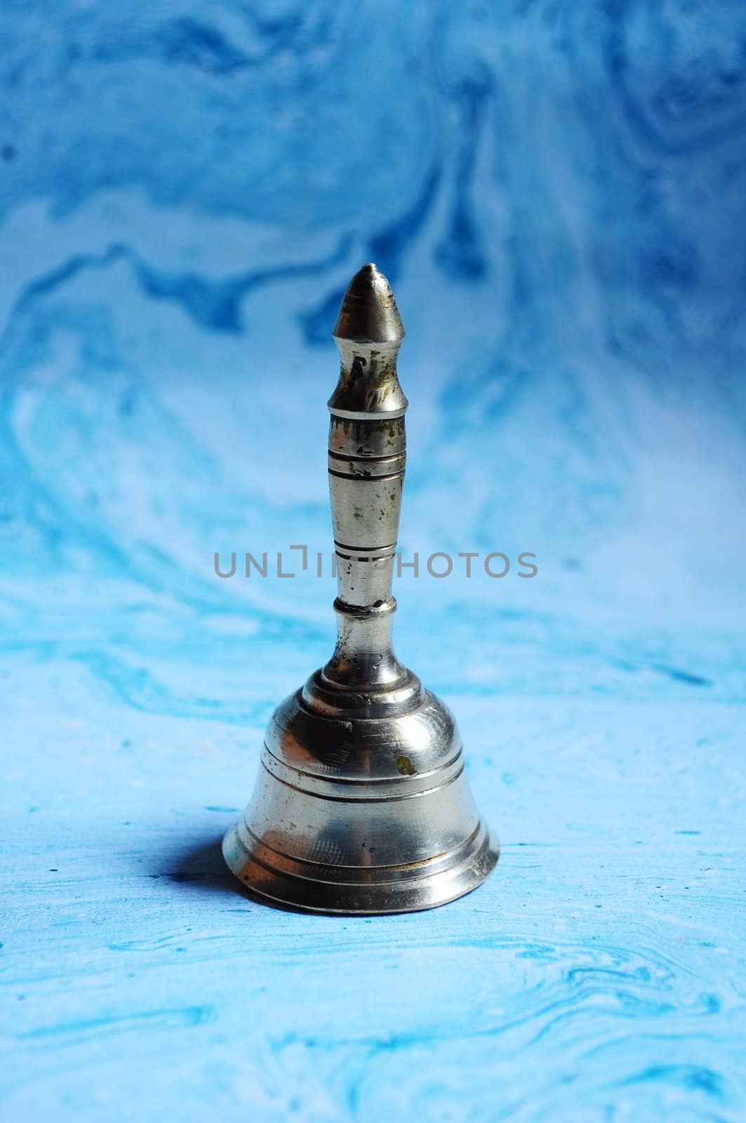  Brass handbell on blue handmade paper Poona, Maharashtra India by snehdep