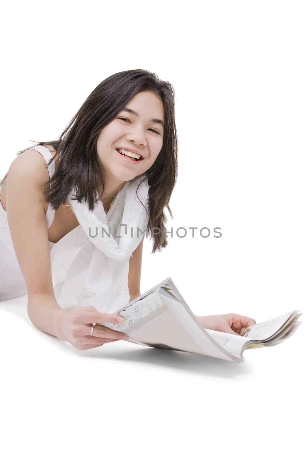 Teen girl in white dress lying down reading a magazine by jarenwicklund