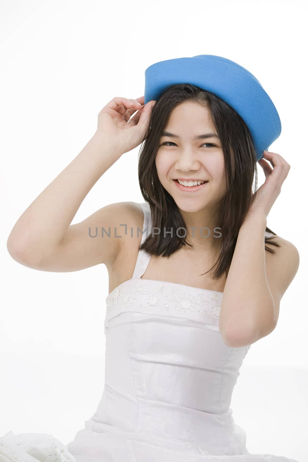 Beautiful young teen girl in blue hat and white dress, smiling. Isolated on white