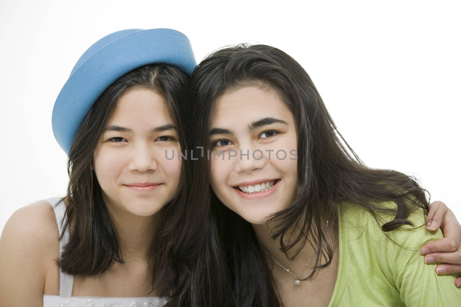Two teen girls smiling together, hugging.