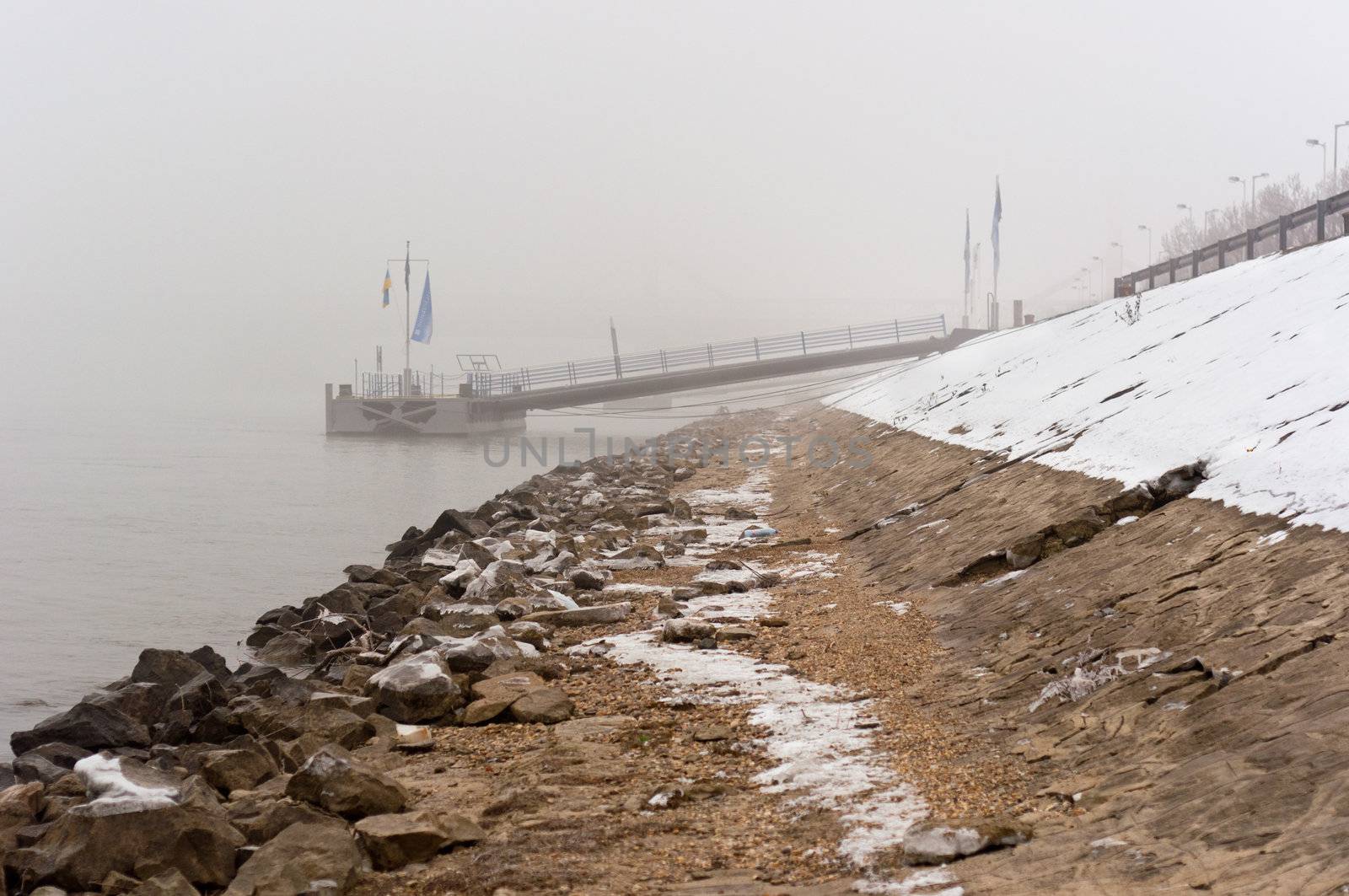 Dirty shore in the fog with jetty in the background by svedoliver