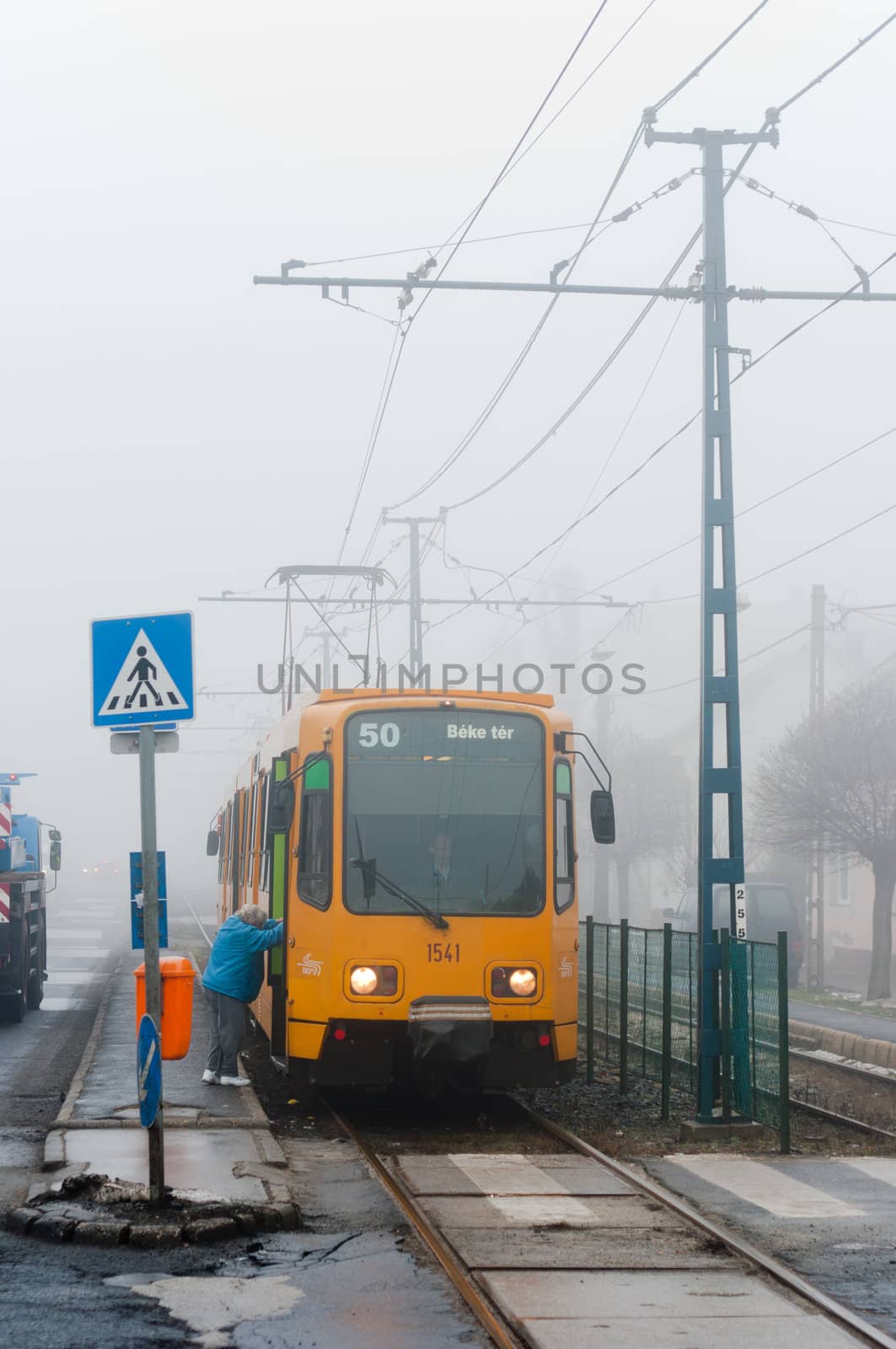 New tram with passanger getting on in the fog
