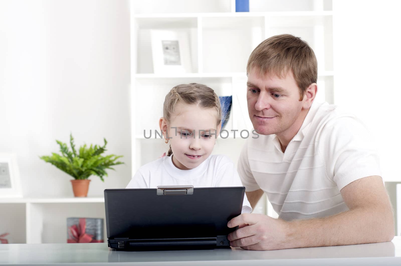 Father and daughter are working together for a laptop at home