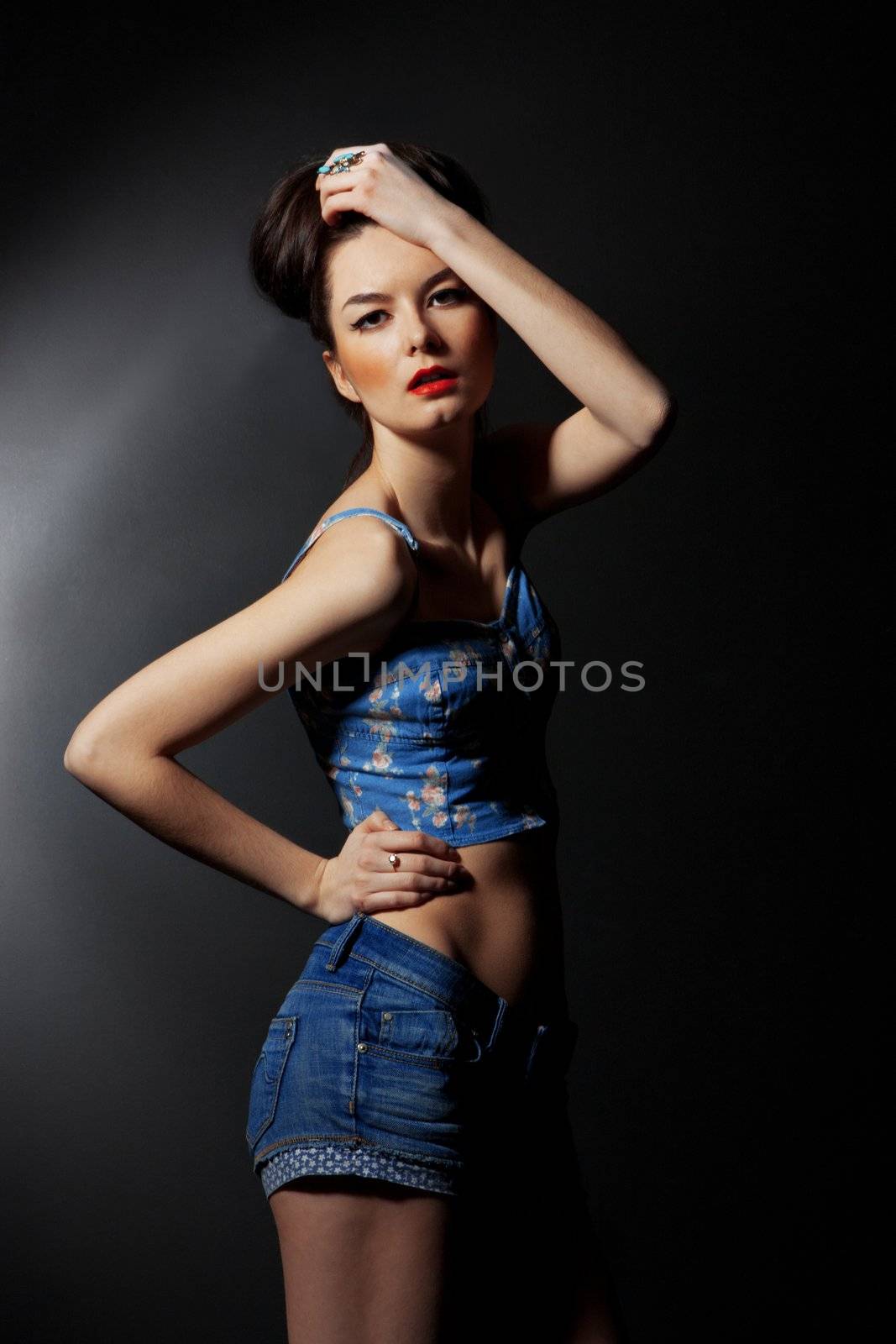 Expressive fashion studio shot of young and beautiful woman wearing brown overcoat on dark background. (Professional makeup and hair style).