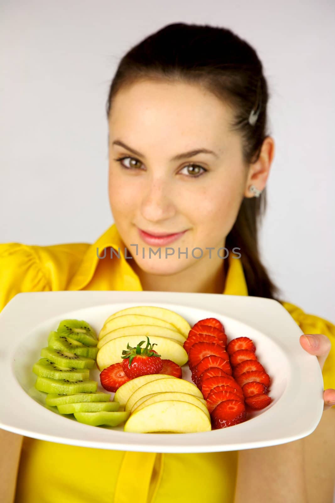 brunette female model showing fresh fruit on a plate by fmarsicano