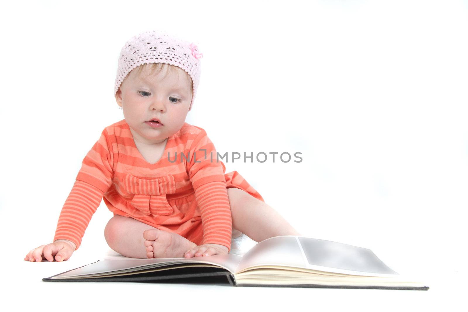 The little blue-eyed girl thumbs through the book. A portrait on a white background. Option 7