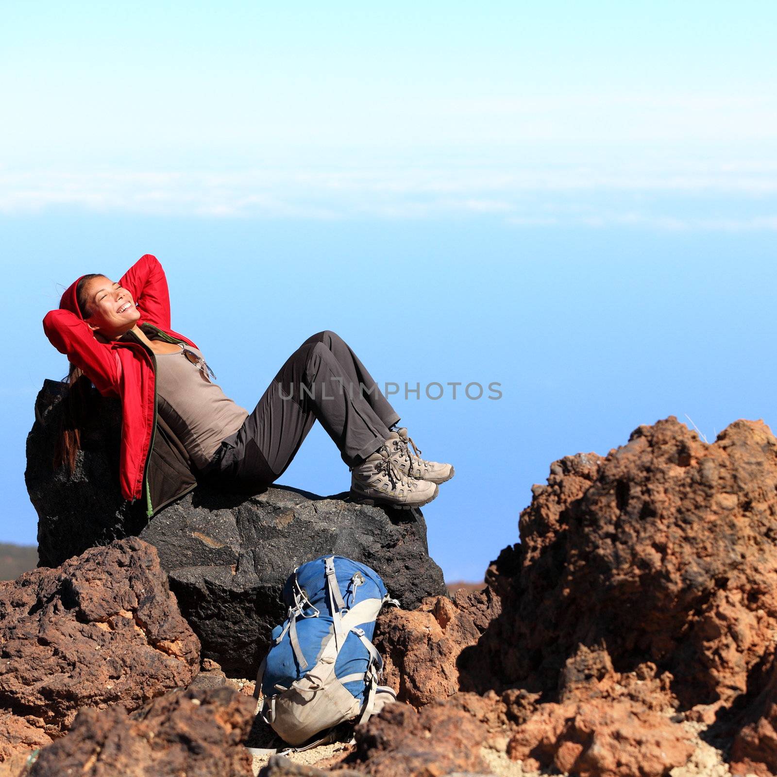 Resting relaxing woman hiker lying down enjoying the sun during hiking travel trek on volcano Teide, Tenerife, Canary Islands, Spain. Beautiful young female hiker.