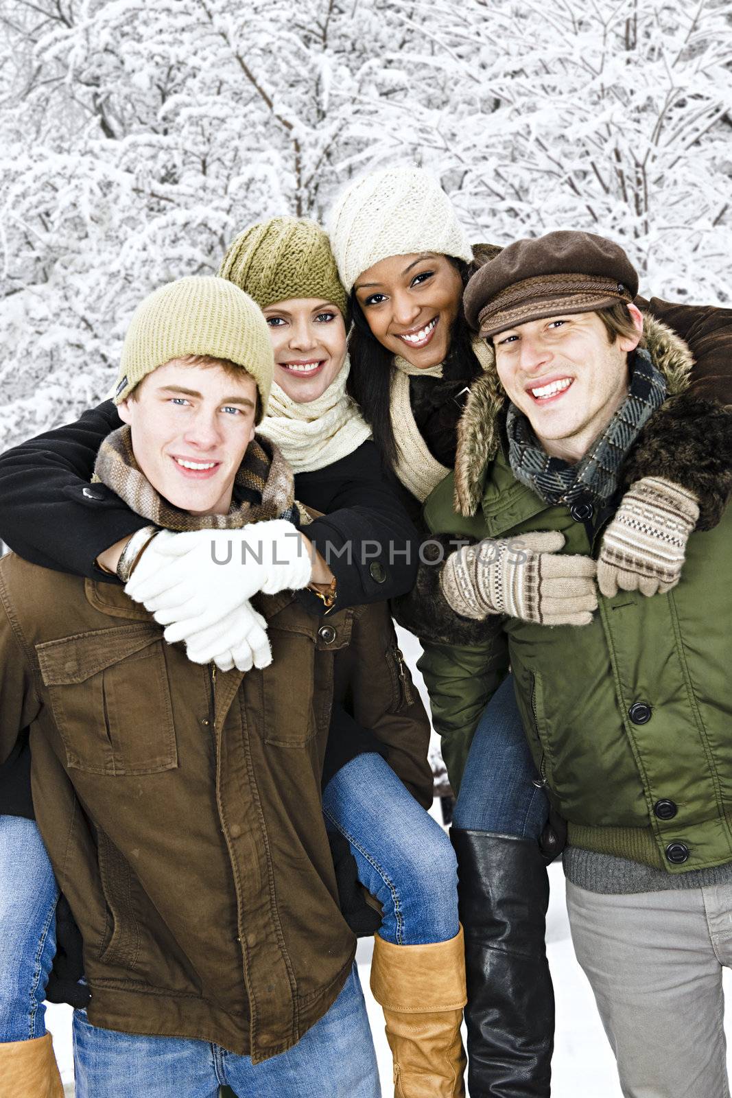 Group of young friends giving piggy back rides outdoors in winter