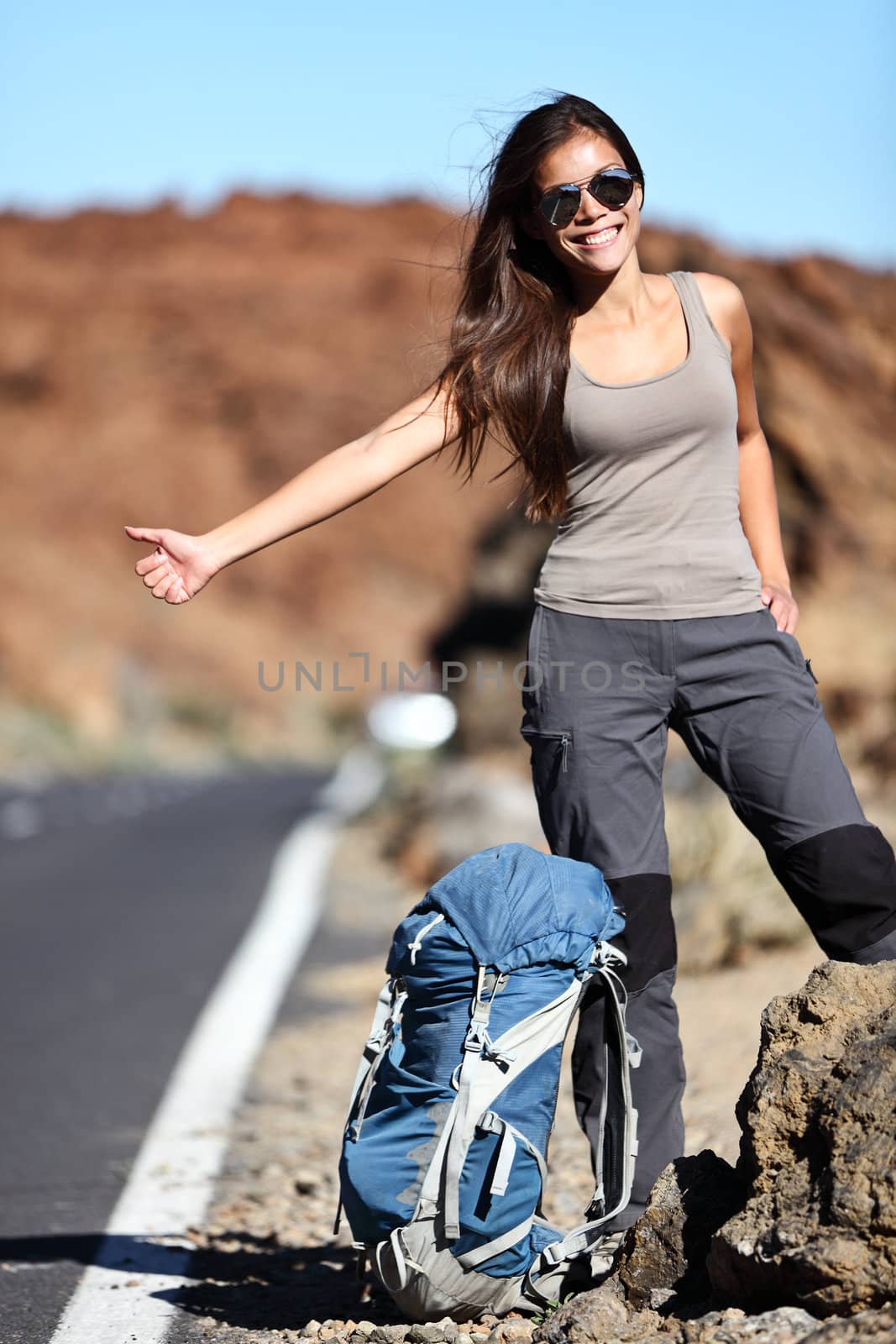 Travel hitchhiker woman happy standing on road side during holiday travel. Beautiful outdoors sporty woman model.