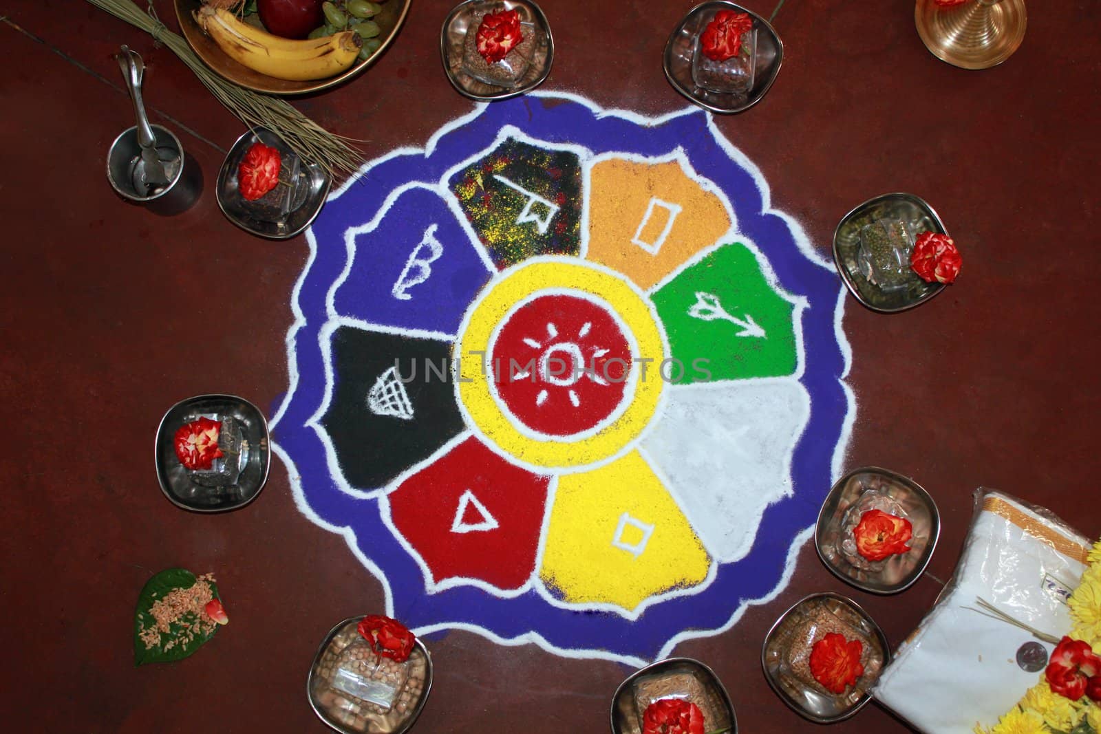 Colorful rangoli art with hindu puja items, flowers, dhoti and money