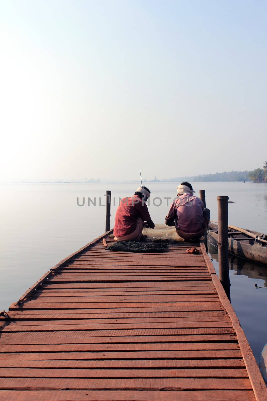 Fishermen sitting on a wooden platform with the fish catch in early moning near cherai village at kochi, kerala, India