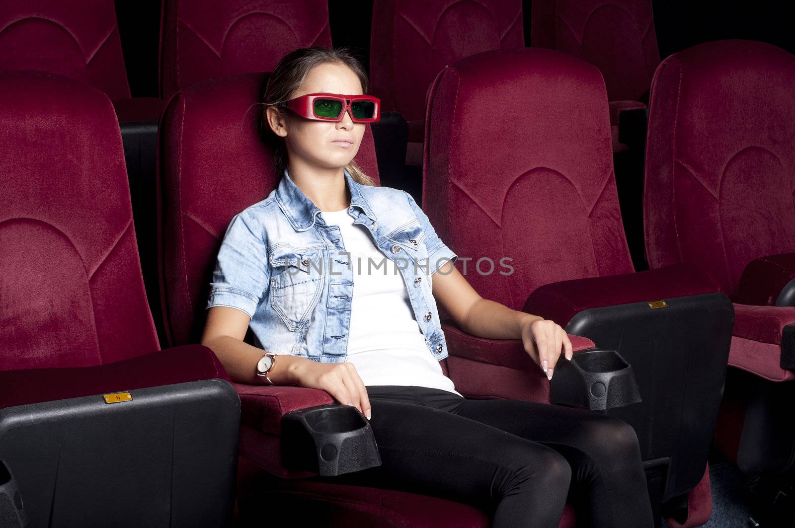 young woman sitting alone in the cinema and watching a movie