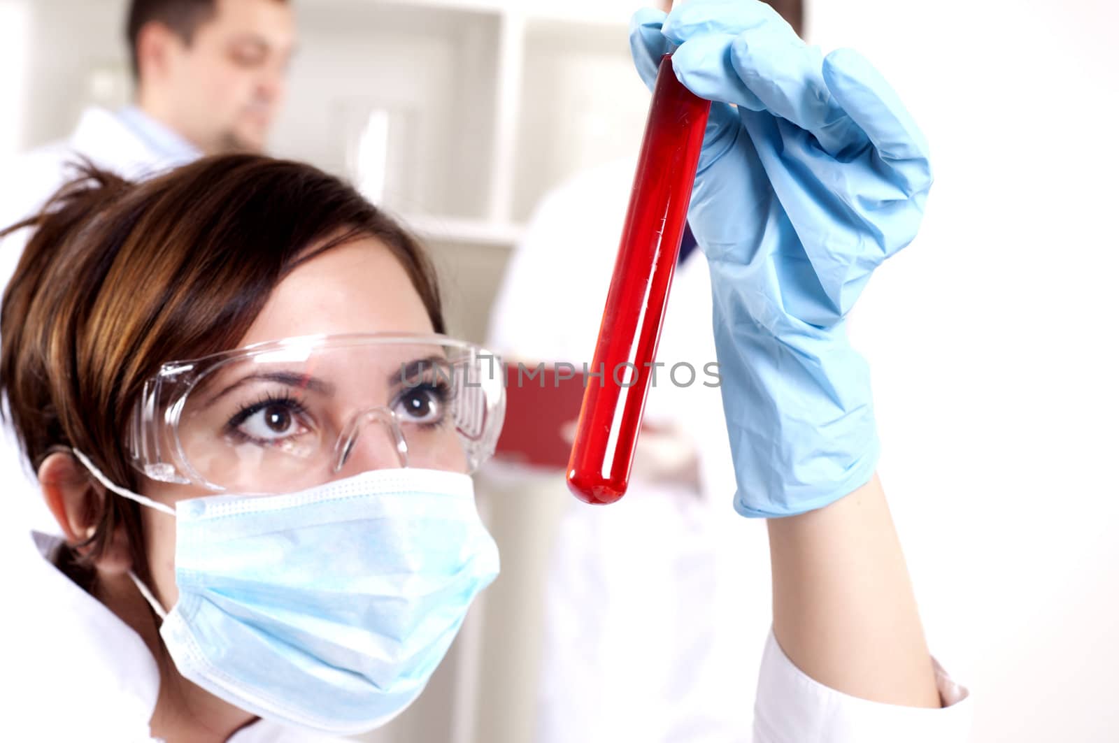 portrait of a beautiful woman chemist, looks at a test tube with red fluid