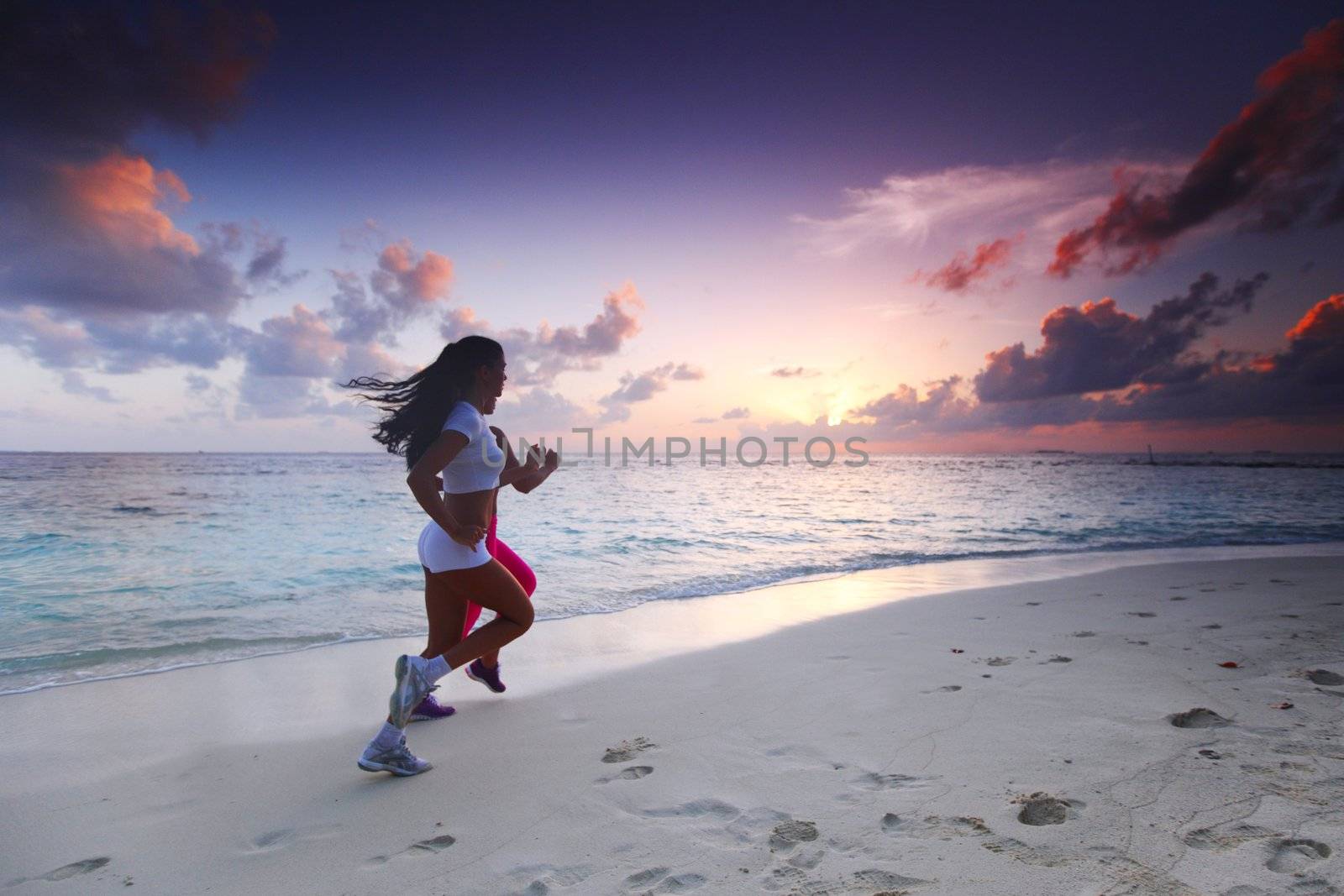 Fitness sport women running on beach at sunset