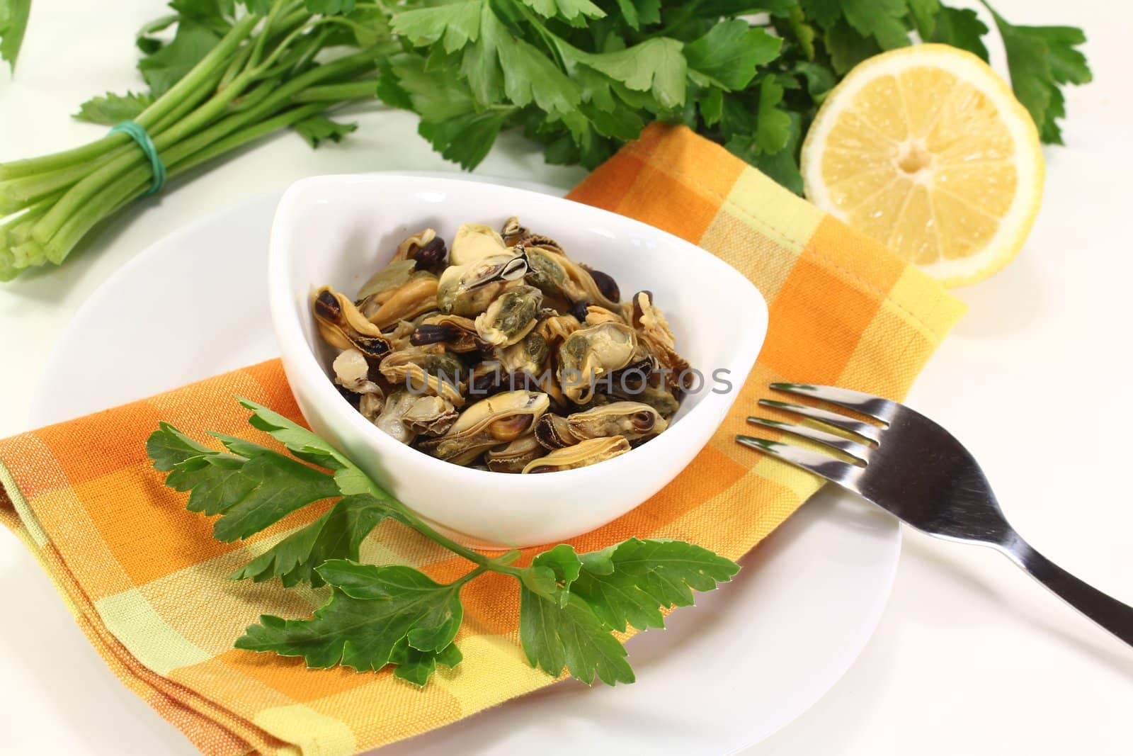 marinated mussels with flat leaf parsley in a bowl on an orange napkin