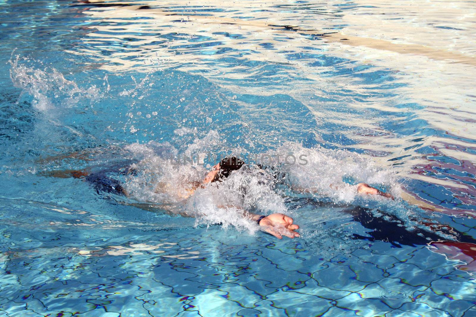 a man swimming backstroke by photochecker
