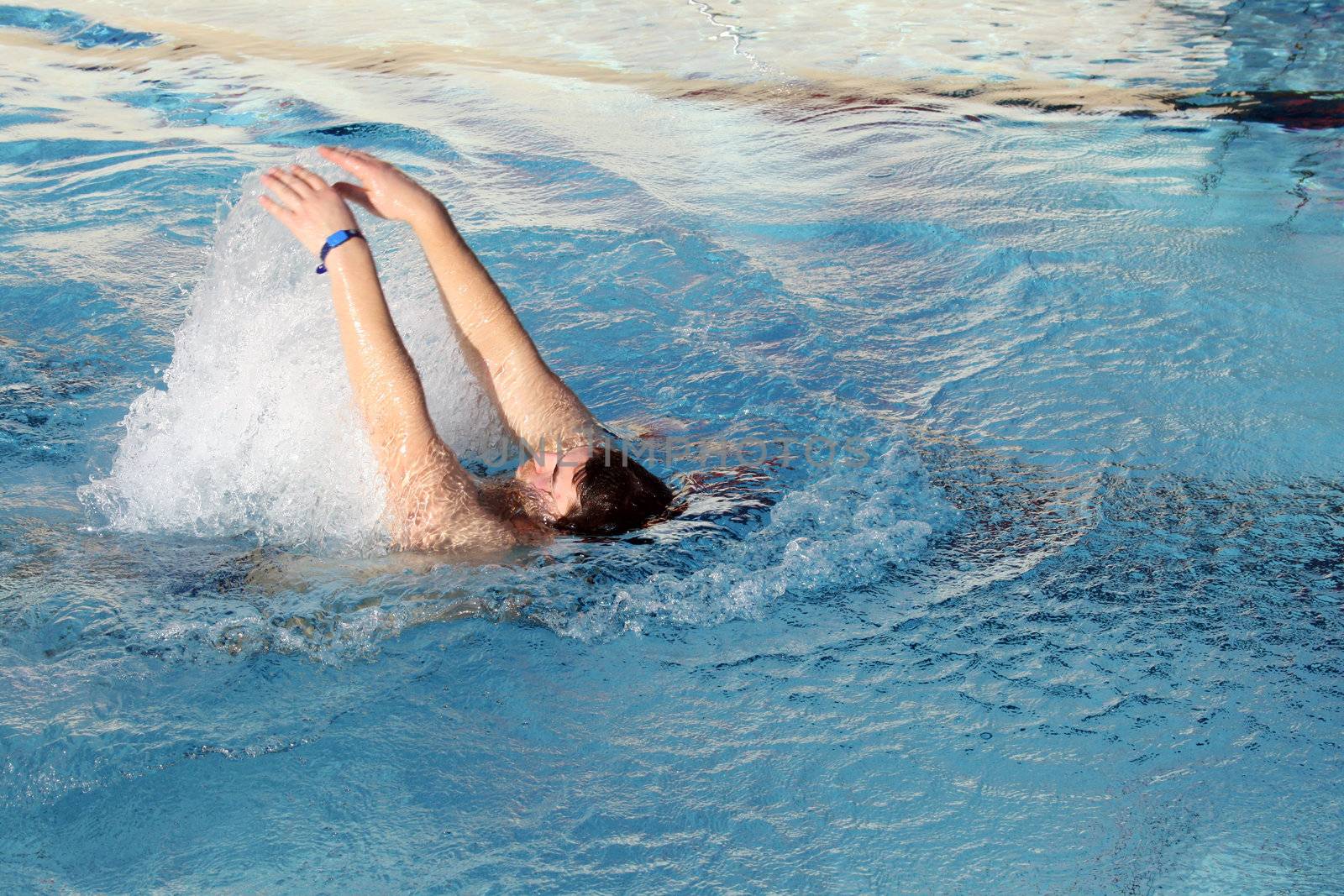 young man swimming backstroke in pool by photochecker