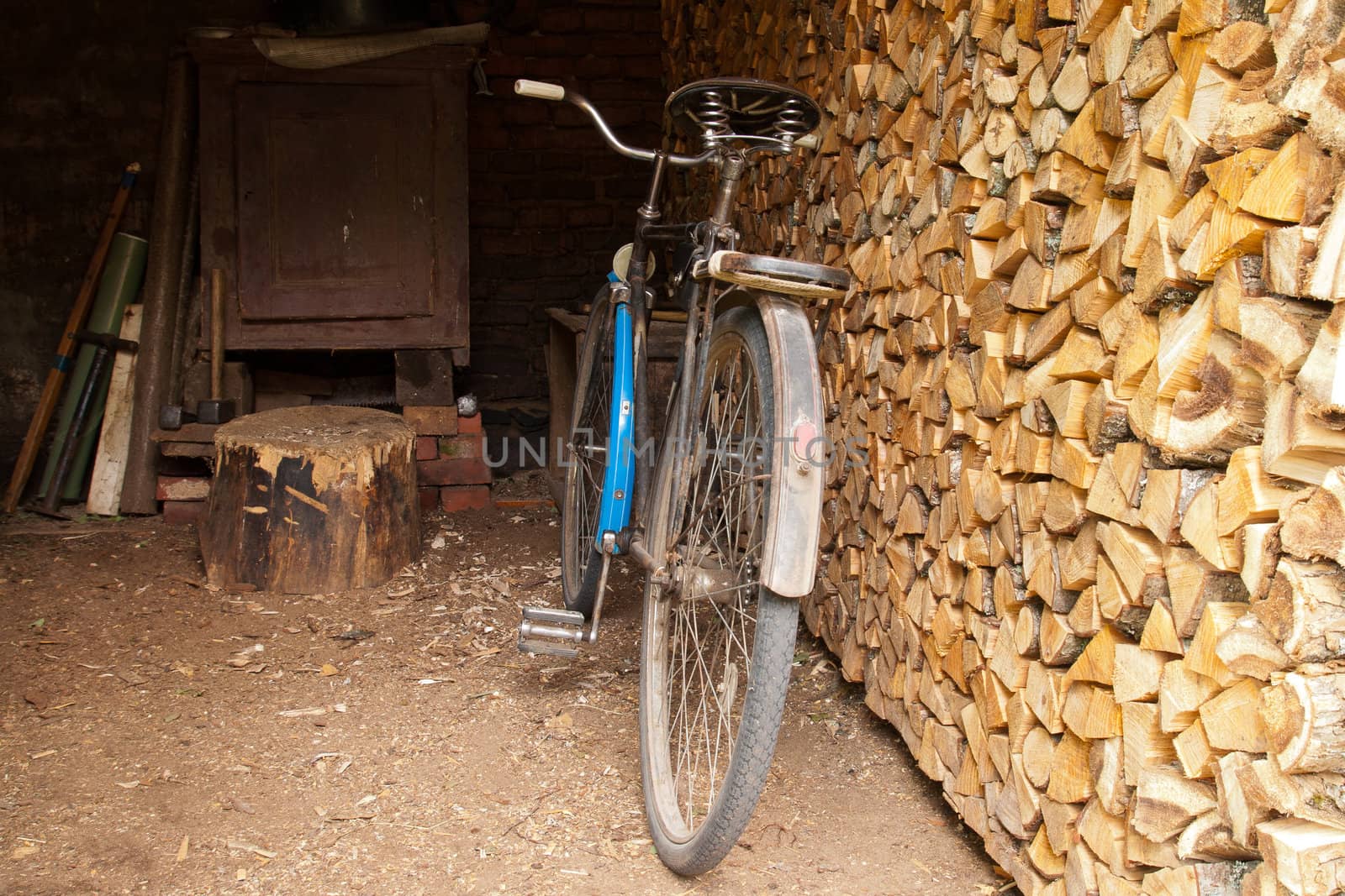 rusty old bicycle in a shed with firewood