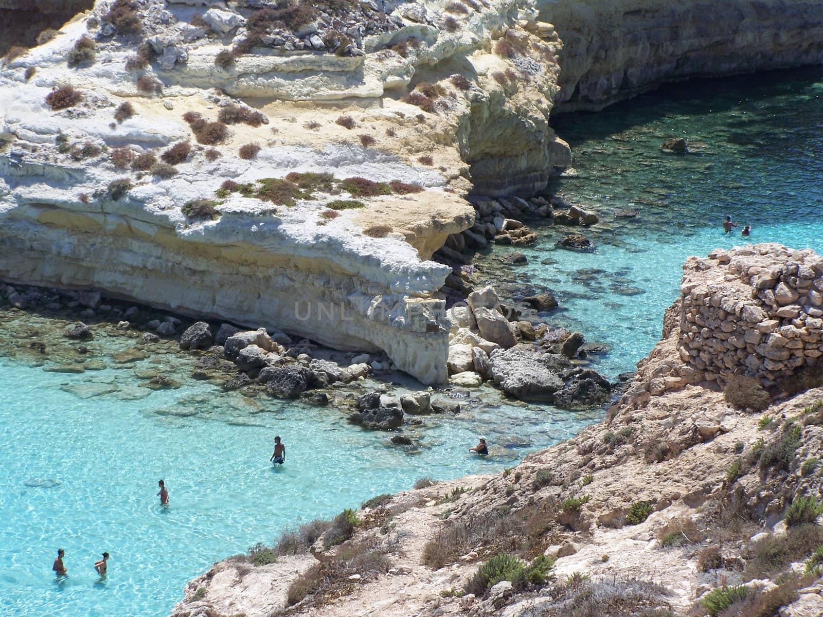 This is the magnificent island of rabbits, in Lampedusa. The water is crystal clear and the sand is white. The rocks are silhouetted against the blue sea and the sky is clear. The depths of this island are a paradise for divers because they are full of colorful fish. 
In this beach nesting turtles, who do travel miles to come to lay their eggs.  This area is protected reserves.