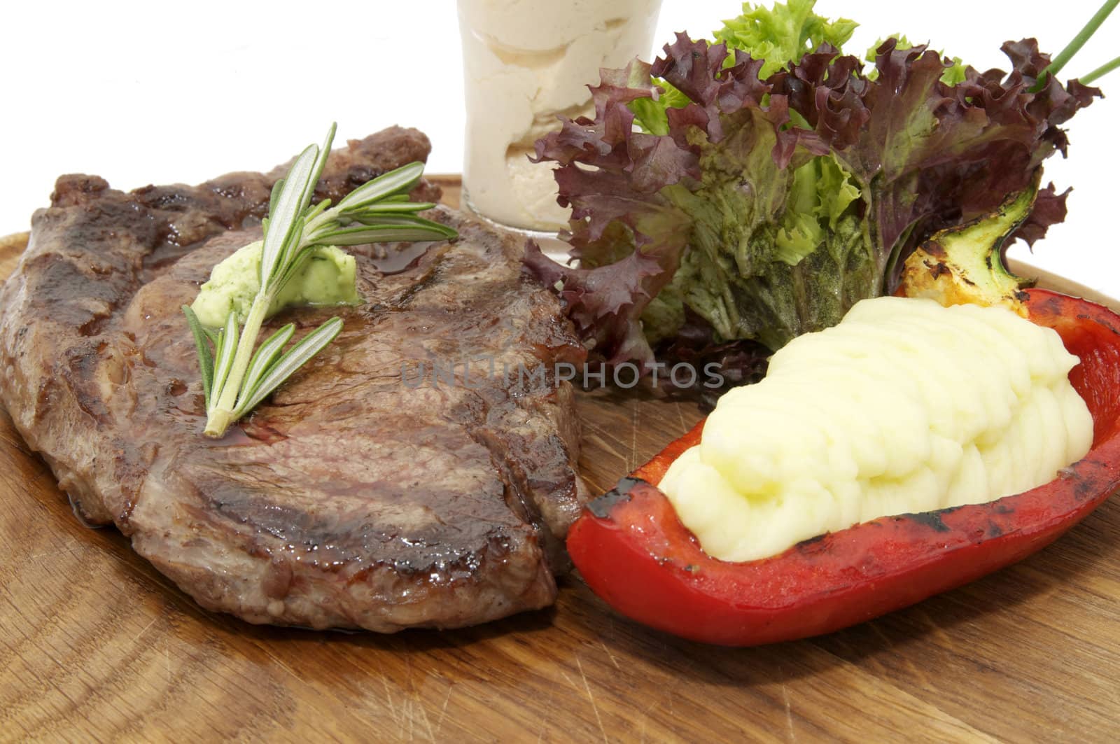 Steak and fresh herbs on a wooden plate over white background